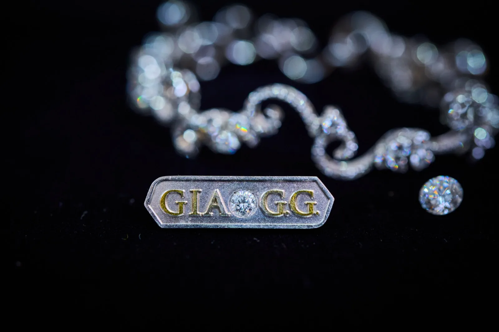ダイヤモンドのブレスレットと並ぶ GIA G.G. のピンバッジ